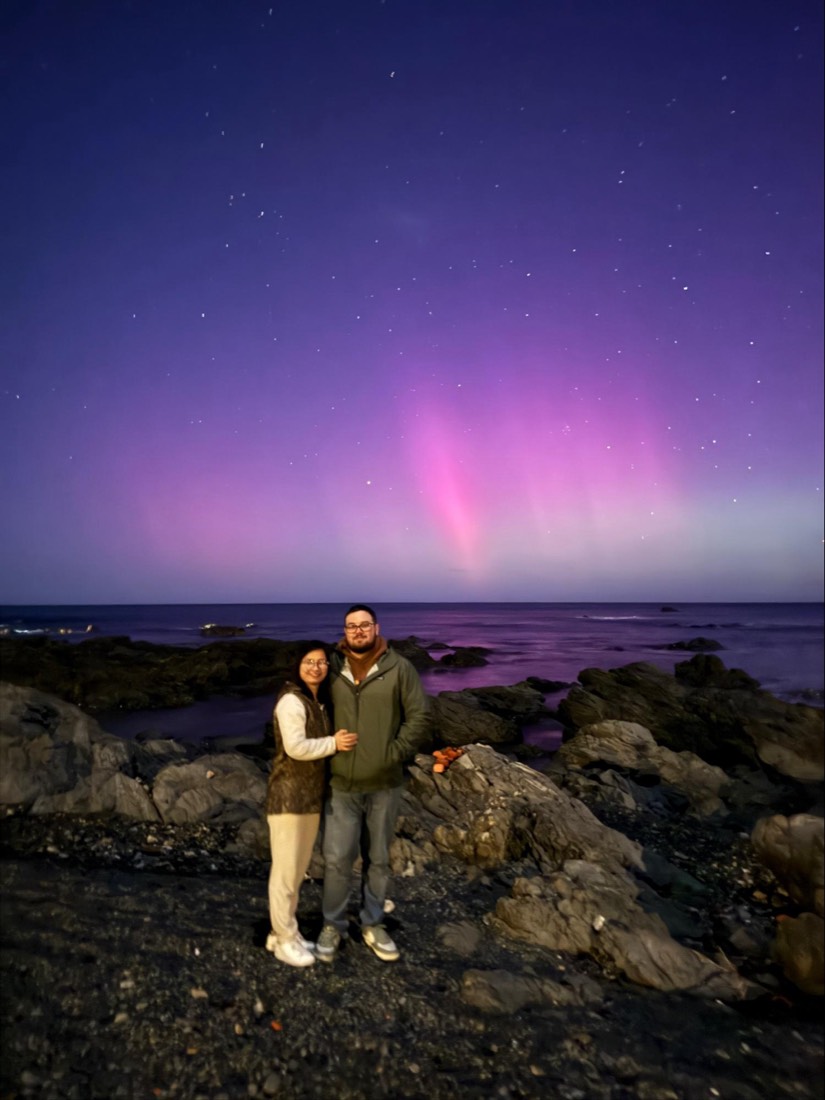 Trang and Robert at Red Rocks under a pink and purple aurora australis