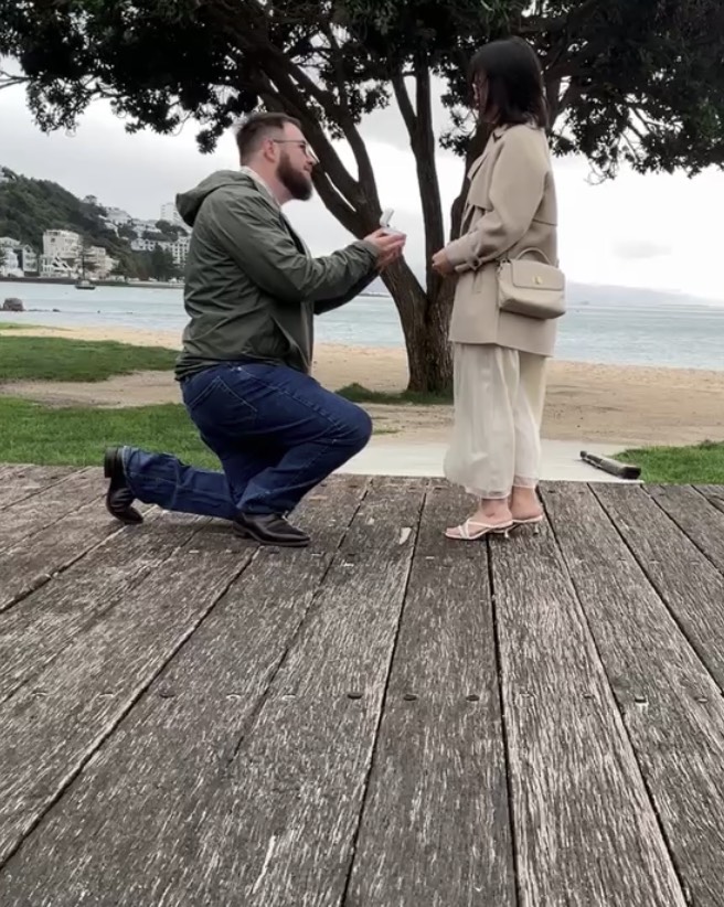 Robert on one knee proposing to Trang on the Wellington waterfront